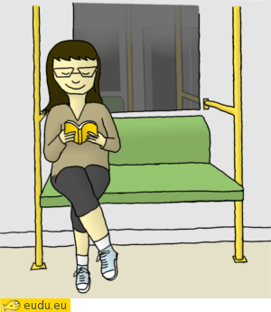 Een meisje zit op een bankje in de metro en leest een boek.